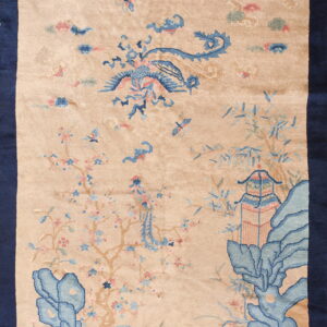 Beige rug with dark blue border featuring a light blue bird, pagoda, and flowering tree pattern.