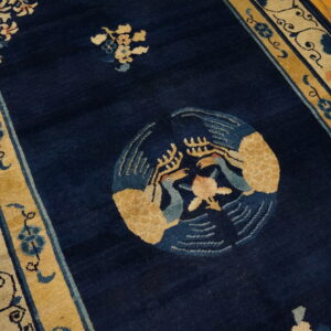 Navy blue rug featuring a golden bird motif and floral borders on light wood floor.
