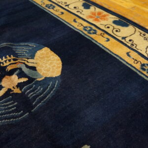 Navy rug with gold and light blue birds, featuring elaborate tan and coral floral borders on wood flooring.
