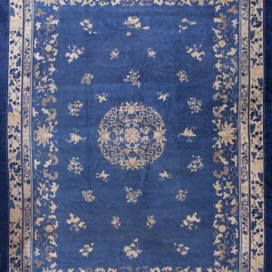 Deep blue rug with a tan floral medallion and scattered motifs across the wide field.