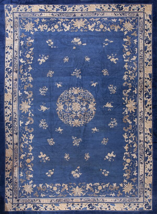Deep blue rug with a tan floral medallion and scattered motifs across the wide field.