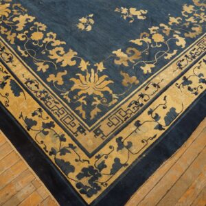 Deep blue rug with contrasting gold and blue floral border and corner motifs rests on wooden planks.