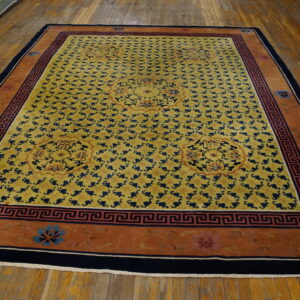 Golden yellow area rug with repeating blue motifs and a rust-orange border lies on wood plank floors.