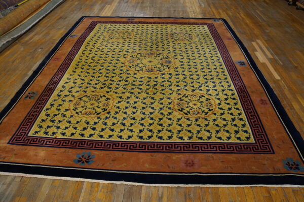 Golden yellow area rug with repeating blue motifs and a rust-orange border lies on wood plank floors.