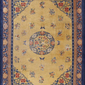 Yellow rug with detailed floral designs, a central medallion, and a wide navy blue and fretwork border.