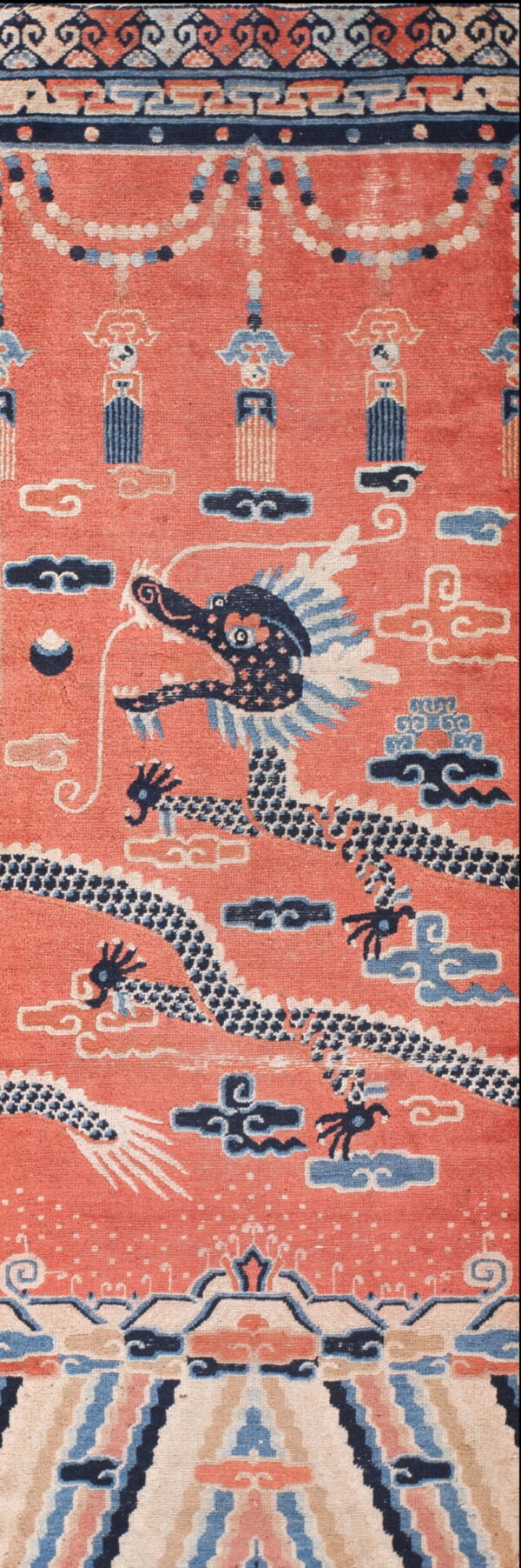 Coral rug with a central dark blue dragon design, light blue clouds, and detailed scroll borders.