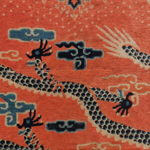 Orange pile rug featuring dark blue dragon and cream-outlined cloud and scale patterns.