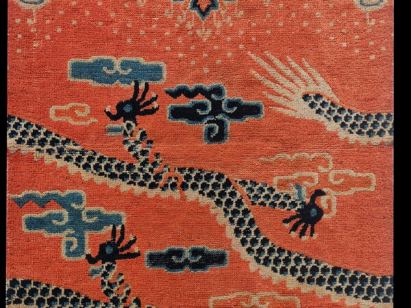 Orange pile rug featuring dark blue dragon and cream-outlined cloud and scale patterns.