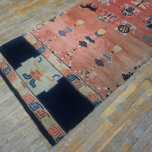 Low-pile salmon and navy runner rug with symbolic patterns rests on distressed gray wood flooring.