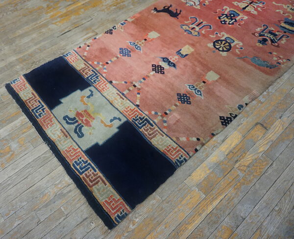 Low-pile salmon and navy runner rug with symbolic patterns rests on distressed gray wood flooring.