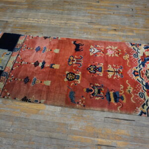 High-pile red runner rug featuring blue and gold symbolic patterns rests on distressed wood flooring.
