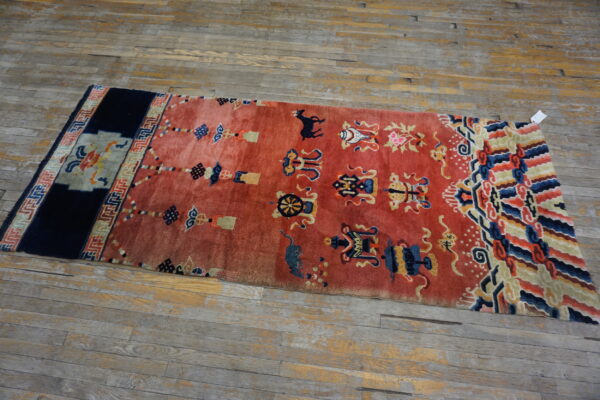 High-pile red runner rug featuring blue and gold symbolic patterns rests on distressed wood flooring.