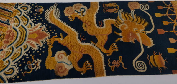 Navy blue rug featuring intricate gold and rust-colored mythological dragons and dense swirling cloud motifs.