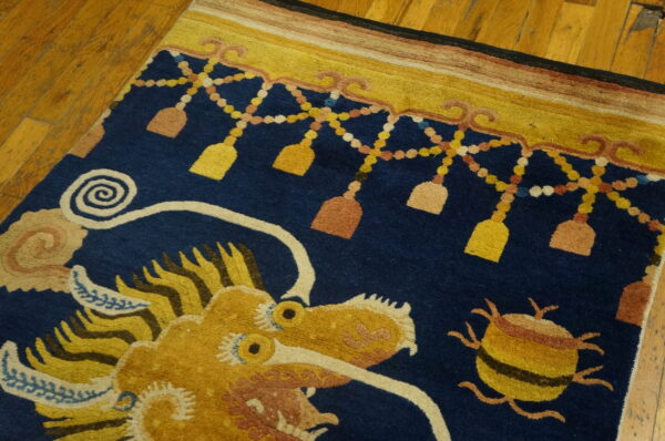 Navy rug with a golden dragon design and tassel border sits on polished wooden floorboards.