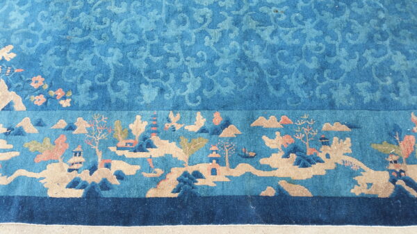 Teal and tan rug featuring a subtle scrolled field and a wide border depicting a detailed scenic landscape.