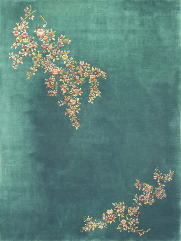 A deep teal rug features asymmetrical branches of colorful pink and yellow blossoms across the field.