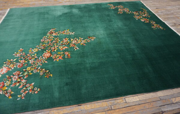 Deep green velvet-look rug featuring scattered multicolored floral sprays resting on plank wood flooring.