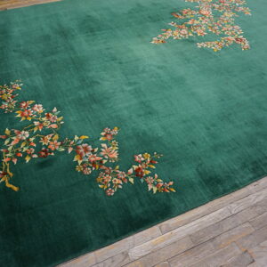 Velvety emerald green rug featuring scattered floral patterns in autumn colors over gray wood planks.