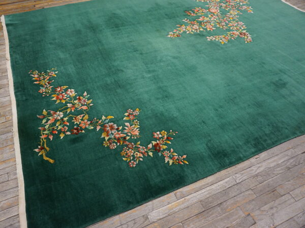 Velvety emerald green rug featuring scattered floral patterns in autumn colors over gray wood planks.