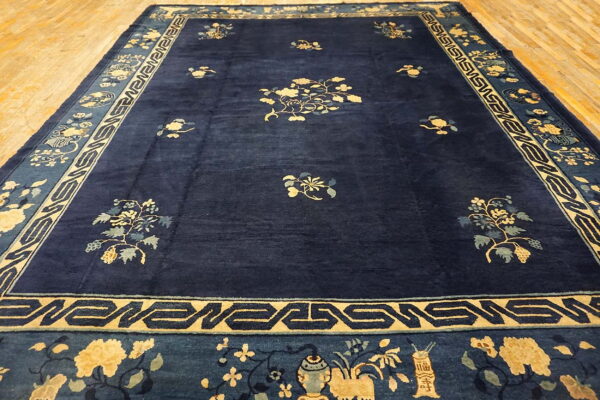 Plush, dark blue rug with gold and teal scattered floral designs and geometric borders.