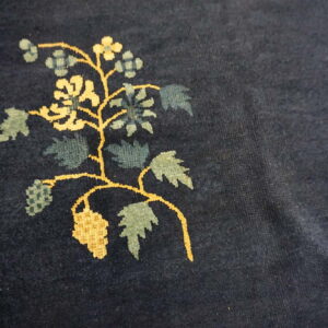 Dark blue plush rug detail showing a yellow and blue-green woven floral vine pattern.