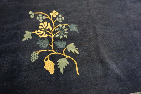 Dark blue plush rug detail showing a yellow and blue-green woven floral vine pattern.