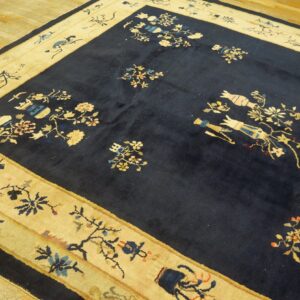 Navy high-pile rug featuring multicolored flower and vase designs within a thick cream border on wood plank floor.