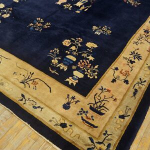 Navy blue rug with a plush pile and wide tan border patterned with intricate floral and pottery designs.