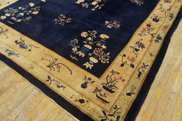 Navy blue rug with a plush pile and wide tan border patterned with intricate floral and pottery designs.