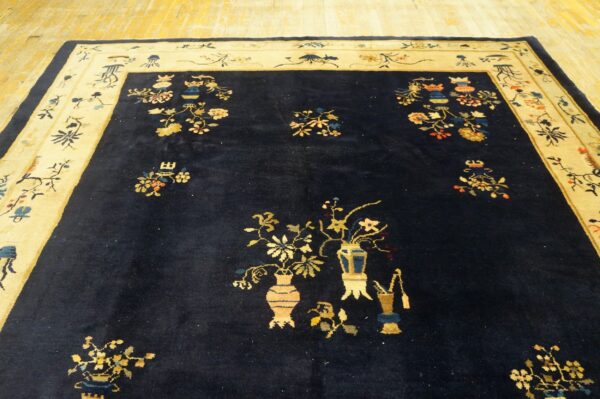 Deep blue rug featuring scattered yellow and multi-colored floral vase designs and a wide pale border.