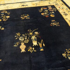 Navy blue rug featuring scattered vase and floral patterns with a wide light yellow border on wood.