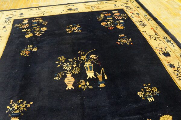 Navy blue rug featuring scattered vase and floral patterns with a wide light yellow border on wood.