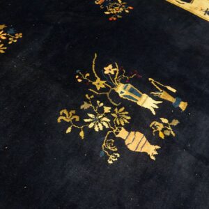 Dark blue rug featuring scattered gold, blue, and tan symbols and florals, with a contrasting cream border visible.