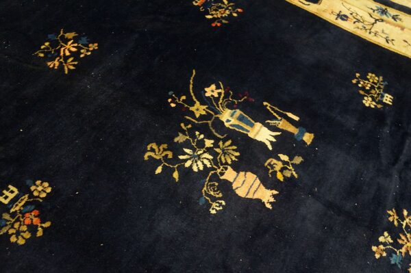 Dark blue rug featuring scattered gold, blue, and tan symbols and florals, with a contrasting cream border visible.