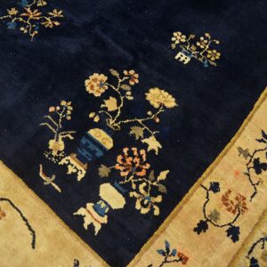 Dark blue high-pile rug detail showing golden-tan borders and multicolored floral vase motifs.