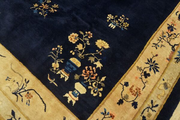 Dark blue high-pile rug detail showing golden-tan borders and multicolored floral vase motifs.