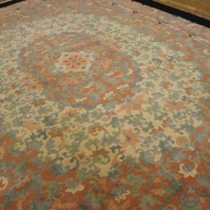 Muted floral rug with rust, cream, dusty blue, and green colors rests on a hardwood floor.