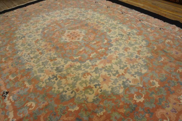 Muted floral rug with rust, cream, dusty blue, and green colors rests on a hardwood floor.