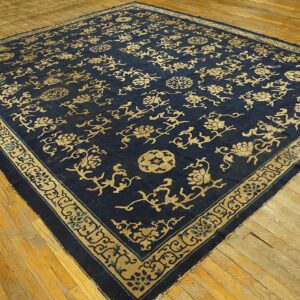 Navy blue rug with intricate gold floral vines and medallions displayed on light wood flooring.