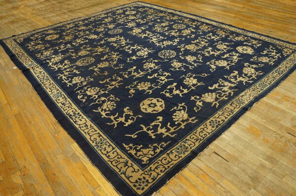 Navy blue rug with intricate gold floral vines and medallions displayed on light wood flooring.