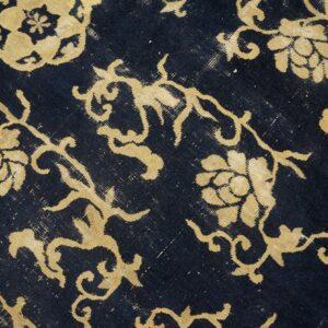 Distressed rug with golden floral and vine motifs against a faded dark blue, low-pile background.