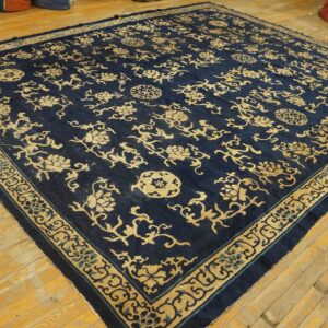 Navy rug featuring an ornate gold floral pattern and detailed border on natural hardwood flooring.