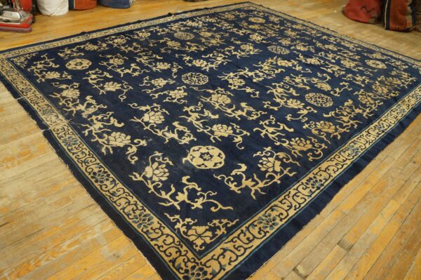 Navy rug featuring an ornate gold floral pattern and detailed border on natural hardwood flooring.