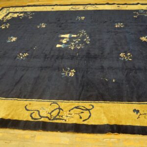 Large navy blue rug with stylized floral motifs and a broad mustard yellow pictorial border on a wood floor.