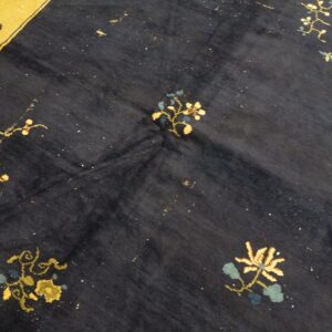 Dark blue rug with scattered floral motifs in golden yellow and blue, featuring a wide yellow border.