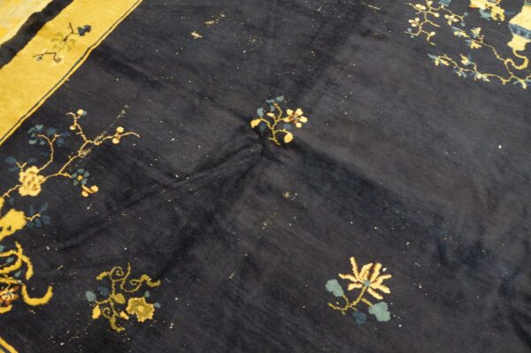 Dark blue rug with scattered floral motifs in golden yellow and blue, featuring a wide yellow border.