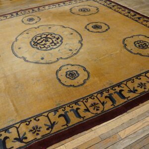 Yellow rug featuring blue medallion motifs and border designs on distressed hardwood flooring.