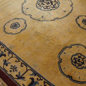Golden yellow rug featuring large blue stylized medallions and a patterned border on a wide plank wood floor.