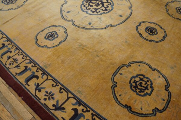 Golden yellow rug featuring large blue stylized medallions and a patterned border on a wide plank wood floor.