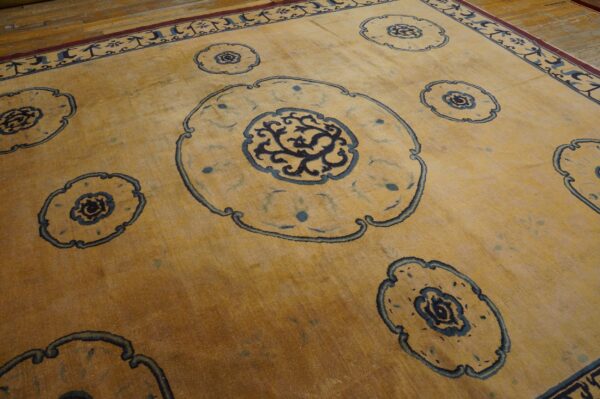 Golden yellow low-pile area rug with dark blue medallions and a decorative border rests on wooden flooring.